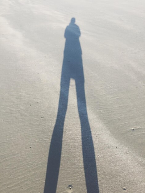 Photo personne de l'ombre sur le sable de la plage