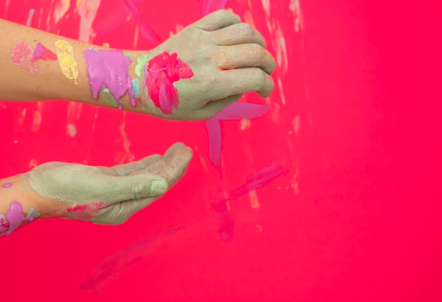 Une personne avec de la peinture sur les mains peint un mur rouge.