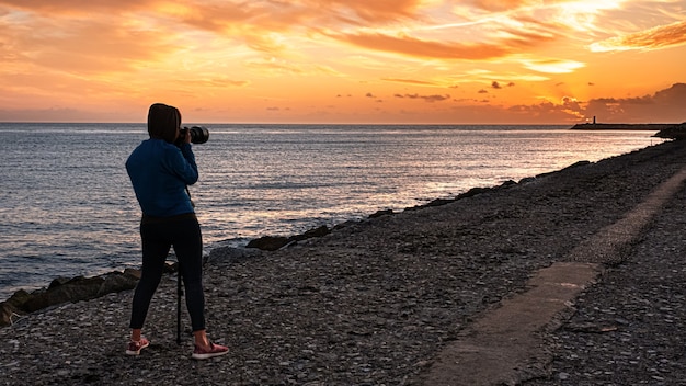 Personne photographiant à la mer au coucher du soleil un jour d'été sur la côte du Portugal à Aveiro