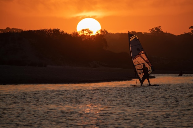 Une personne sur une planche de surf avec le soleil se couchant derrière elle