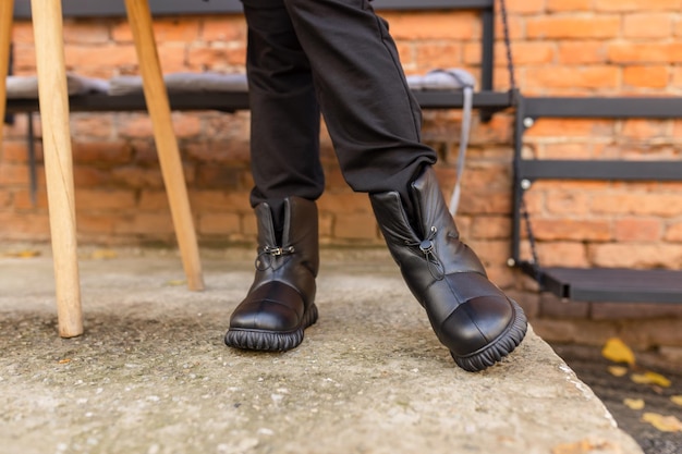 Photo une personne portant des bottes en cuir noir se tient debout sur une surface en béton.