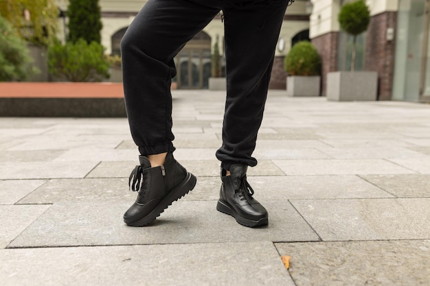 Une personne portant des chaussures noires et une paire de bottes en cuir noir.
