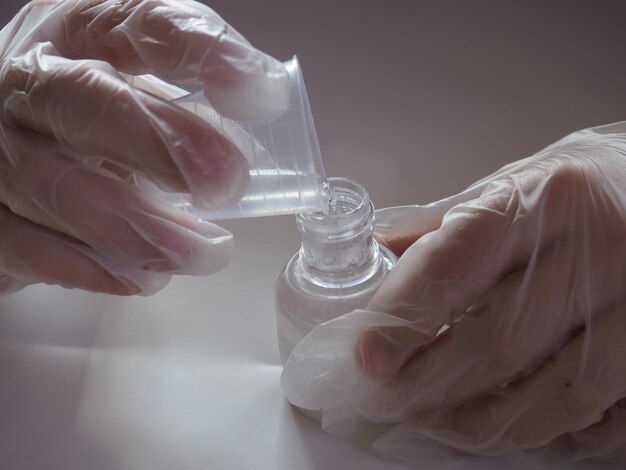 Une personne pose une bouteille de vernis à ongles sur une table.