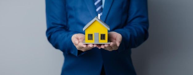 Une personne pose sa main sur un modèle de maison miniature photo du concept d'assurance habitation lors de l'achat d'une nouvelle maison devrait avoir une assurance habitation pour être sûr s'il y a un danger pour la maison