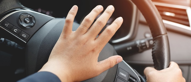 Personne poussant le klaxon en conduisant assis d'une voiture de presse au volant, klaxonnant pour avertir les autres personnes dans le concept de circulation.