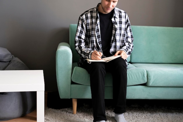 Une personne prenant des notes dans le livre restant à la maison