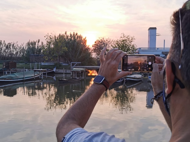 Une personne prend une photo du soleil dans un coucher de soleil d'automne