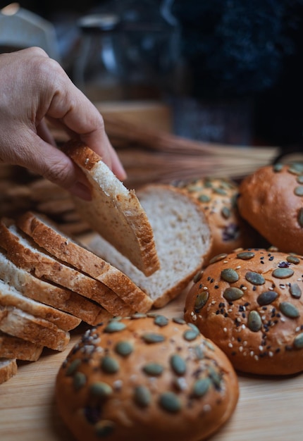 Une personne prend une tranche de pain sur une table avec des pains et d'autres pains.
