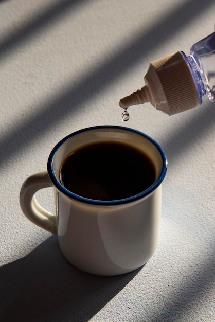 personne qui adoucit son café avec un édulcorant liquide