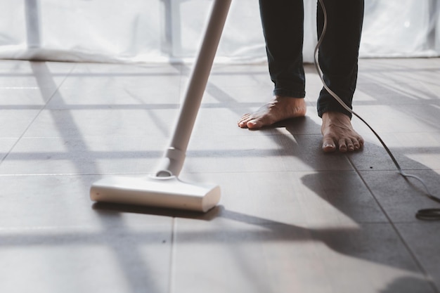 La personne qui nettoie la salle de nettoyage utilise un aspirateur pour nettoyer le sol du salon dans le bureau de l'entreprise Personnel de nettoyage Maintien de la propreté dans l'organisation