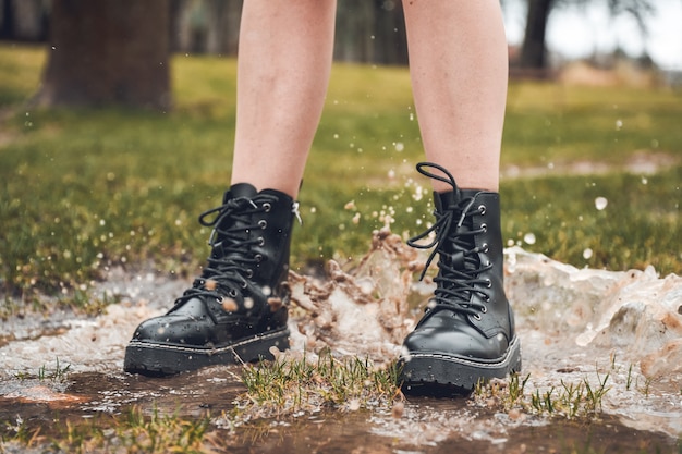 Personne sautant par-dessus une flaque d'eau dans le parc