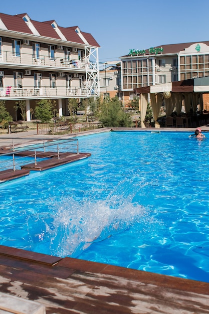 Une personne saute dans la piscine et la personne porte un chapeau.