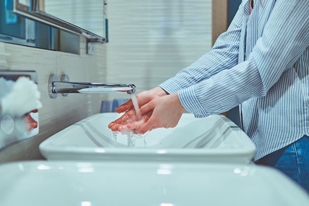 Personne se laver les mains sous l'eau courante dans la salle de bain