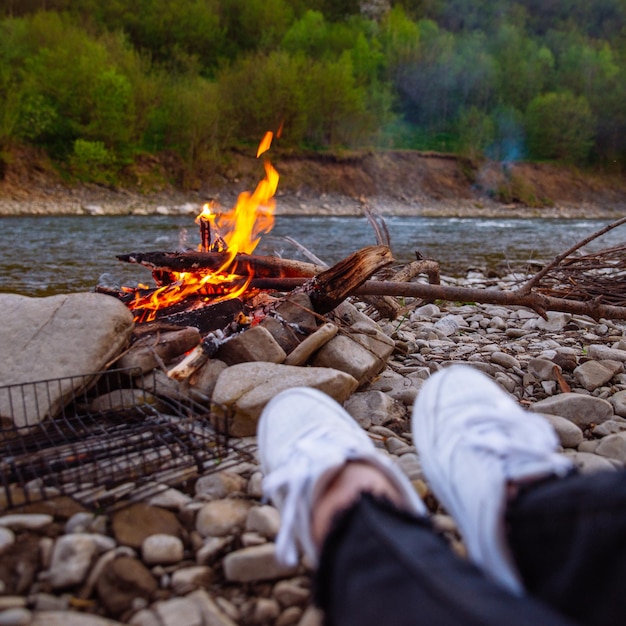 Personne se reposant près de la rivière avec concept de randonnée au feu de camp