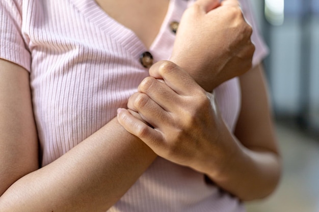 Une personne se tient au poignet, ce qui provient de la douleur au travail, de la douleur due au fait de s'asseoir et de taper sur un ordinateur pendant une longue période, provoquant des douleurs dans de nombreuses zones du corps. Notion de syndrome de bureau.