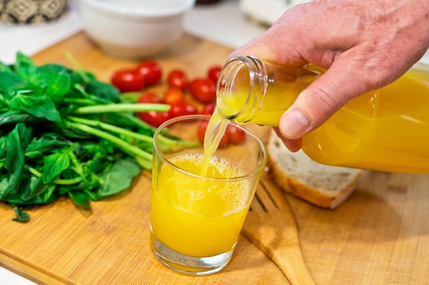 Personne servant du jus d'orange naturel dans la cuisine.