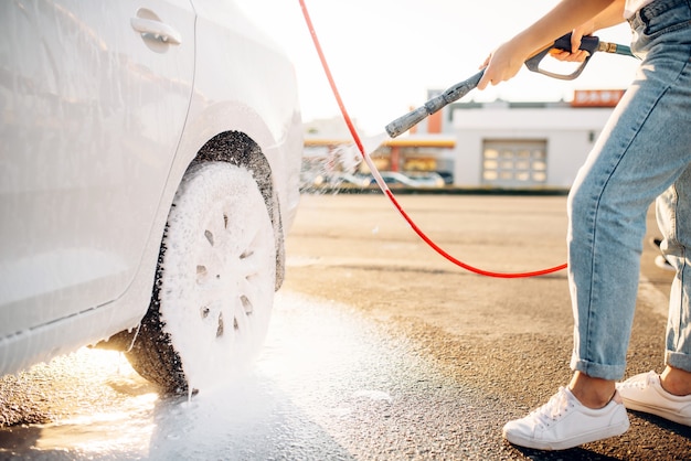 Personne de sexe féminin avec pistolet à eau laver la mousse