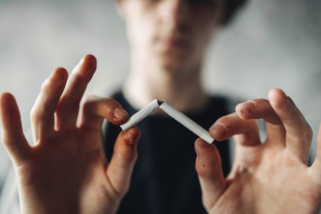 Personne de sexe masculin accro casse une cigarette