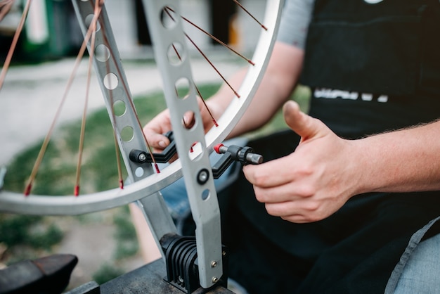 Personne de sexe masculin ajuste les rayons et la roue du vélo