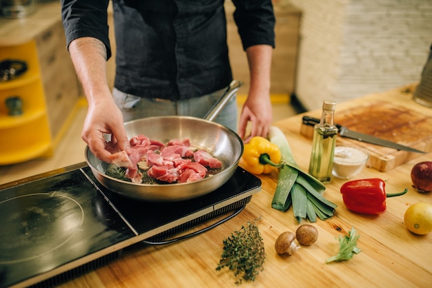 Personne de sexe masculin la cuisson de la viande avec des herbes et des assaisonnements dans une casserole