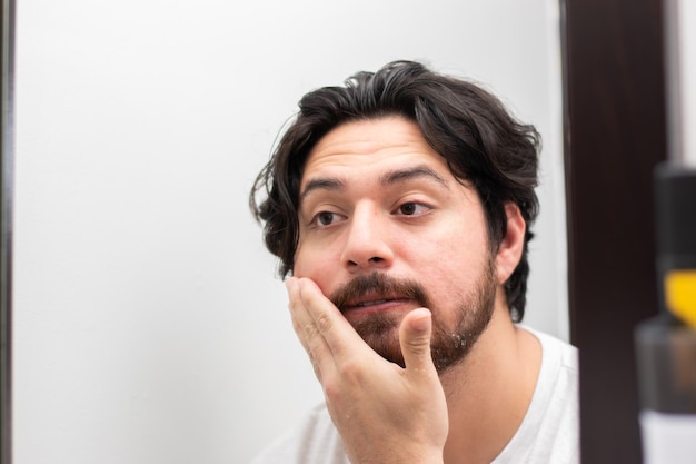 Personne de sexe masculin nettoyant et lavant son visage pour se raser en regardant dans un miroir avec espace de copie