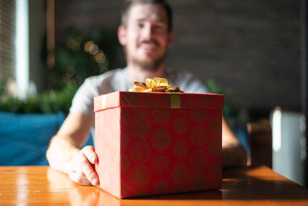 Une personne de sexe masculin tenant une boîte cadeau rouge la veille de Noël