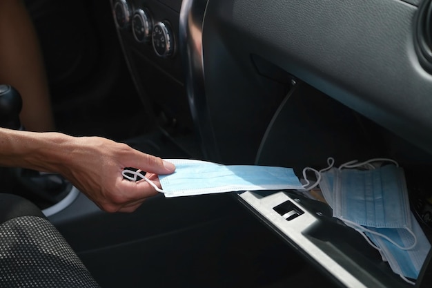 une personne sort un masque médical de la boîte à gants de la voiture