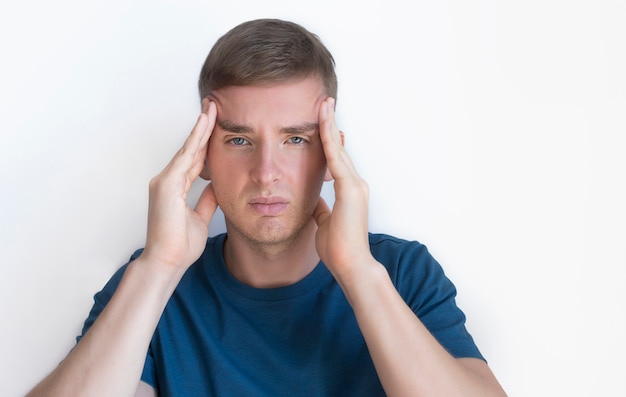 Personne souffrant de douleur en raison de maux de tête sévères, de migraine. Beau mec sympa, jeune homme contrarié agacé tenant sa tête avec les mains, les tempes avec les doigts,. Expression du visage