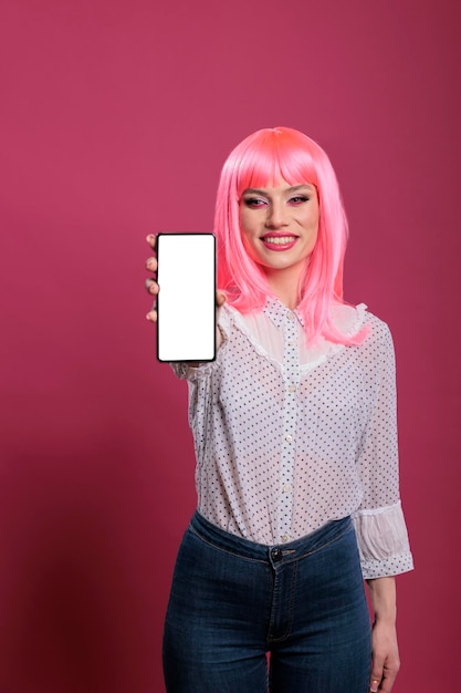 Personne Souriante Aux Cheveux Roses Montrant Un Smartphone Avec écran Blanc Et Affichage De Clé Chroma Isolé Devant La Caméra. Tenant Un Modèle De Maquette De Fond Vierge Sur L'application De Téléphone Mobile.