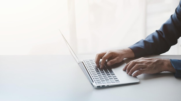 Personne tapant sur un clavier d'ordinateur portable homme d'affaires travaillant sur un ordinateur portable il tape des messages à des collègues et fait une fiche d'information financière pour résumer la réunion