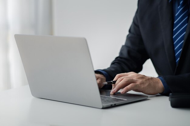 Personne tapant sur un clavier d'ordinateur portable homme d'affaires travaillant sur un ordinateur portable il tape des messages à des collègues et fait une fiche d'information financière pour résumer la réunion