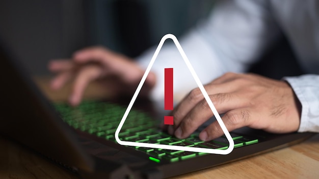 Une personne tapant sur un clavier avec un point d'exclamation à l'écran.