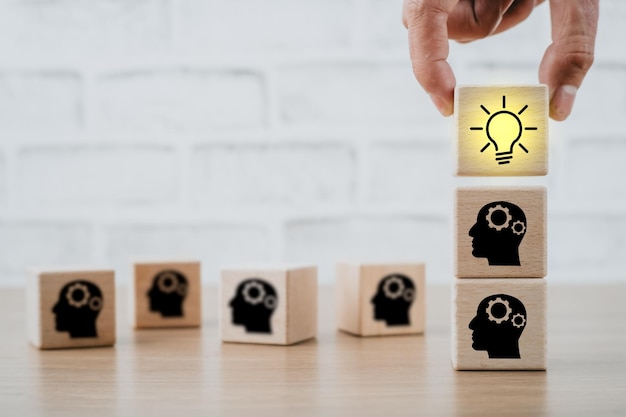 Personne tenant une ampoule à la main et icône de personnes sur un cube en bois avec un espace de copie Concept idée créative et idée d'innovation Travail d'équipe