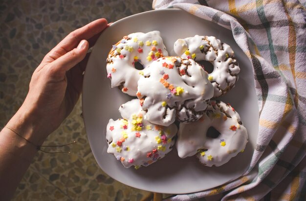 Une personne tenant une assiette de beignets avec des vermicelles dessus