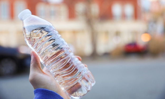 Une personne tenant une bouteille d'eau dans ses mains.