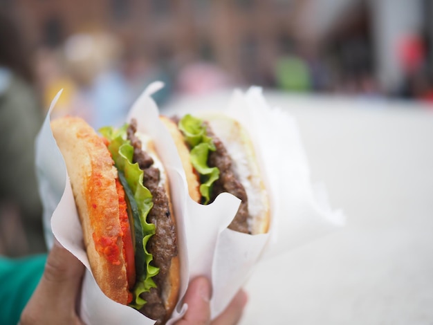 Une personne tenant deux hamburgers avec de la laitue dessus.