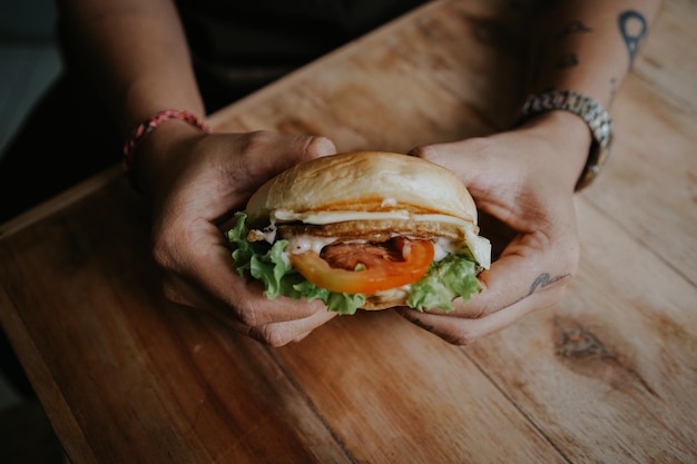 Une personne tenant un hamburger avec un œuf au plat dessus