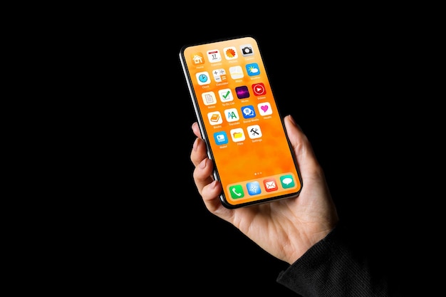 Personne tenant à la main un téléphone portable avec des exemples d'icônes d'application sur l'écran d'accueil Isolé sur fond noir