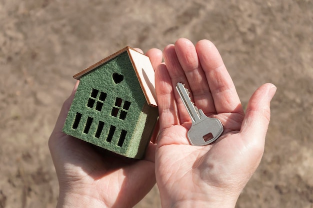 Une personne tenant une maison avec une clé à la main