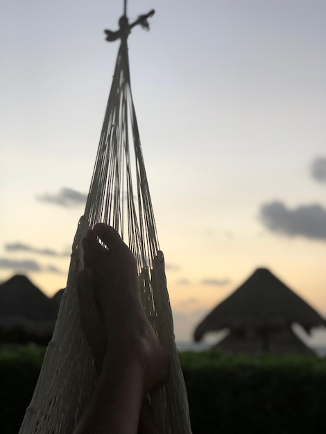 Photo personne tenant un parapluie sur un hamac contre le ciel au coucher du soleil