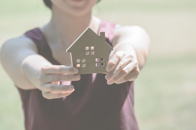 personne tenant une petite maison