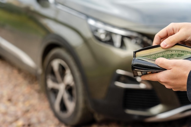 Une personne tenant un portefeuille dans les mains se tient devant un prêt d'assurance automobile et achète un concept de financement automobile