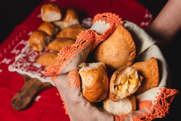 Personne tenant un récipient en tissu avec des empanadas et des petits pains.