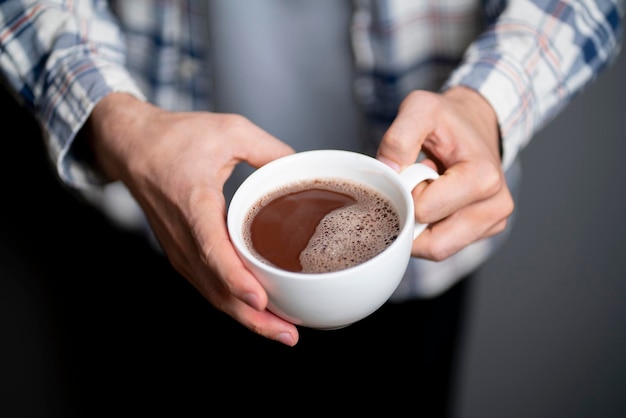 Une personne tenant une tasse de café blanche et la buvant par une froide journée d'hiver