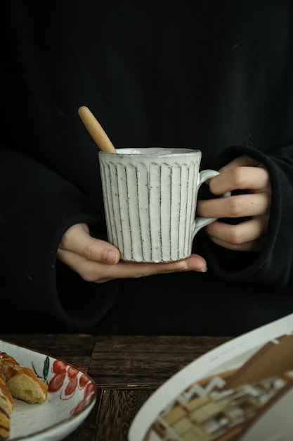 Une personne tenant une tasse de café avec une cuillère en bois