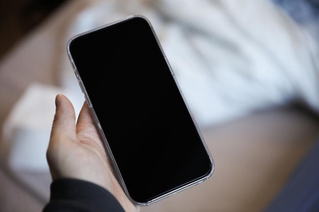 Une personne tenant un téléphone avec un écran noir qui dit "iphone"