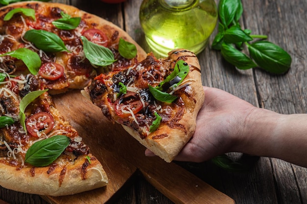 Une personne tenant une tranche de pizza avec une bouteille d'huile d'olive sur le côté.