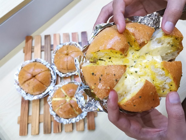 Une personne tient un bagel avec du fromage dessus.