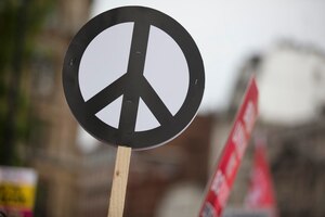 Une personne tient une bannière de signe de paix lors d'une manifestation