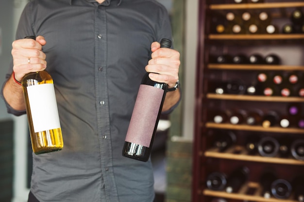 Une personne tient des bouteilles de vin blanc et rouge dans un magasin d'alcools